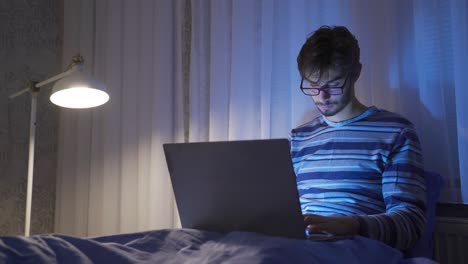 Adolescente-Usando-Una-Computadora-Portátil-En-La-Cama,-Sin-Dormir-Y-Cansado.
